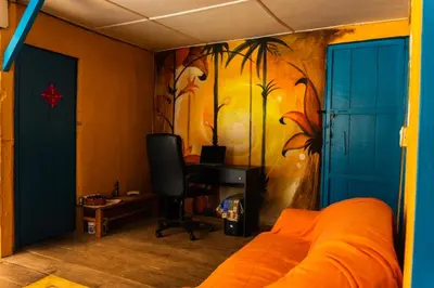 a bedroom with an orange bed and a desk with a painting at Parcerito's Hostel in Jericó