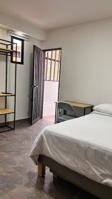 a bedroom with a bed and a desk and a window at Casa hotel Los Laureles in Medellín