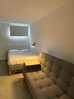 a bedroom with a couch and a bed with a window at Casa hotel Los Laureles in Medellín