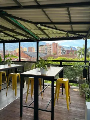 a patio with tables and yellow chairs on a deck at Casa hotel Los Laureles in Medellín