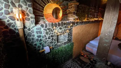 a room with a stone wall with a toilet paper dispenser at BioHotel Ecohouse in Guarne
