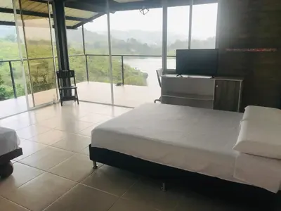 a bedroom with a bed and a desk and windows at El Espume de San Juan by JR in Guatapé