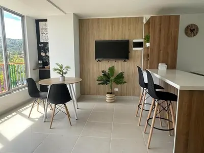 a living room with a table and chairs and a television at Apartamentos Avenida del malecón, frente al lago. Guatape in Guatapé