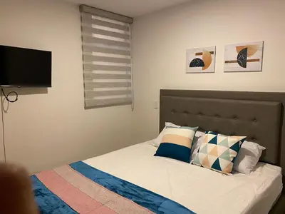 a bedroom with a bed with a flat screen tv at Apartamentos Avenida del malecón, frente al lago. Guatape in Guatapé