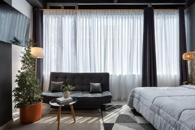 a bedroom with a couch and a large window at Lexum by Bernalo Hotels in Medellín