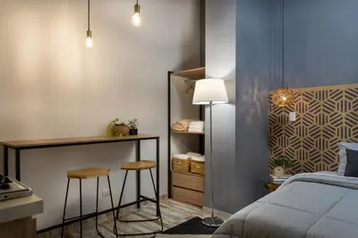 a bedroom with a bed and a desk and two stools at Lexum by Bernalo Hotels in Medellín