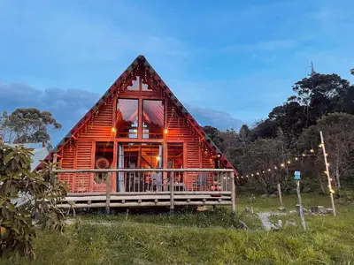 a log cabin with a porch in a field at BRUMA BLANCA CHALETS in Medellín