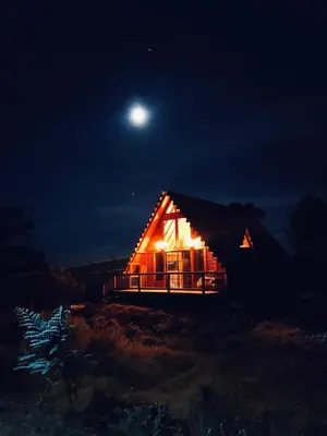 a house lit up at night with the moon in the sky at BRUMA BLANCA CHALETS in Medellín