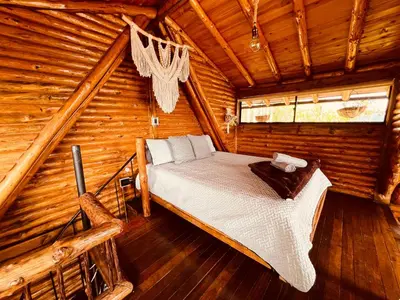 a bed in a room in a log cabin at Skyline Ecoliving Santa Elena in Santa Elena