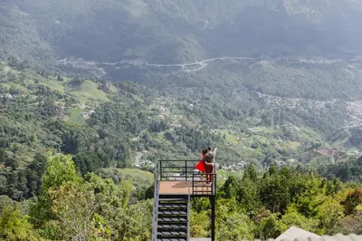 a person sitting on top of a ladder overlooking a valley at Skyline Ecoliving Santa Elena in Santa Elena