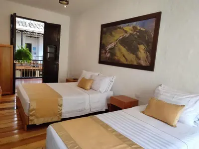 a hotel room with two beds and a painting on the wall at Hotel Boutique La Leyenda 1860 in Salamina