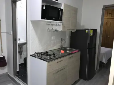 a small kitchen with a stove and a refrigerator at Aparta estudio amoblado 3 Medellin, San joaquin in Medellín