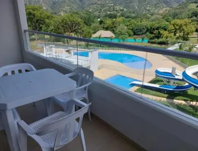 a balcony with a table and chairs and a swimming pool at Apartamento Citadela Di Sole Santa fe De Antioquia in Santa Fe de Antioquia