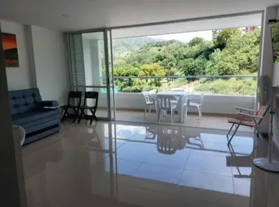 a living room with a table and chairs and a large window at Apartamento Citadela Di Sole Santa fe De Antioquia in Santa Fe de Antioquia