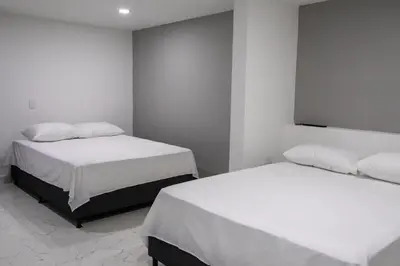 two beds in a room with white walls at Nómada Hospedaje in San Rafael