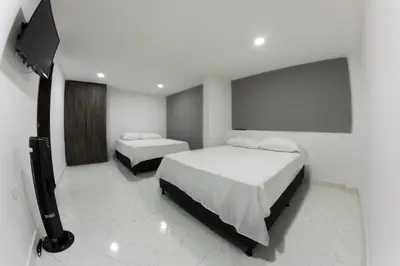 a white room with two beds and a television at Nómada Hospedaje in San Rafael