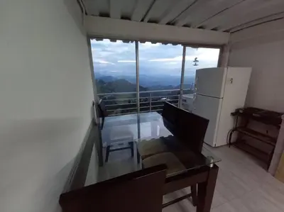 a room with a table and a refrigerator and a balcony at Apartamento Campestre y Turístico con Garaje y Mirador in Manizales