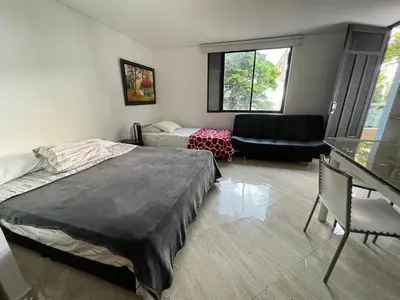 a bedroom with a bed and a living room at En Laureles con ascensor , balcón y muy bien ubicado en laureles Medellín , EL BARRIO MAS COOL DEL MUNDO in Medellín