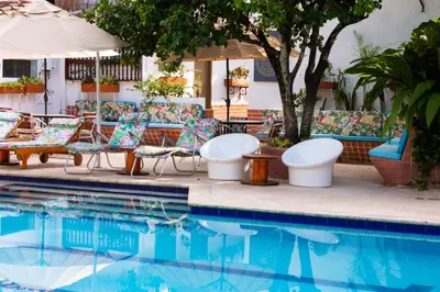 a pool with chairs and a table and an umbrella at Entre Palmas Casa Hotel in Santa Fe de Antioquia