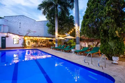 a swimming pool with green chairs next to a building at Entre Palmas Casa Hotel in Santa Fe de Antioquia