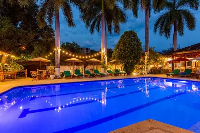 a swimming pool at night with palm trees at Entre Palmas Casa Hotel in Santa Fe de Antioquia