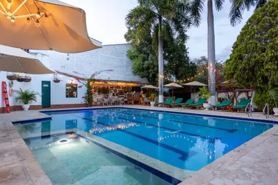 a pool at a hotel with chairs and an umbrella at Entre Palmas Casa Hotel in Santa Fe de Antioquia