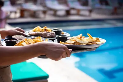 a person holding a plate of food next to a pool at Entre Palmas Casa Hotel in Santa Fe de Antioquia