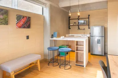 a kitchen with a bar with stools and a refrigerator at Loft 43 in Medellín