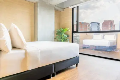 a bedroom with a white bed and a large window at Loft 43 in Medellín