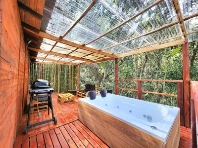 a large bath tub on a deck with a pergola at Cabaña en Medio del Bosque con Jacuzzi - Santa Elena in Santa Elena