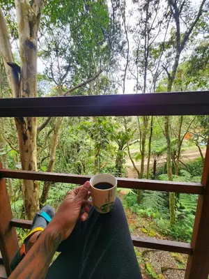 a person is holding a cup of coffee at Cabaña en Medio del Bosque con Jacuzzi - Santa Elena in Santa Elena