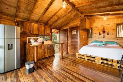 a bedroom with a bed in a wooden cabin at Cabaña en Medio del Bosque con Jacuzzi - Santa Elena in Santa Elena