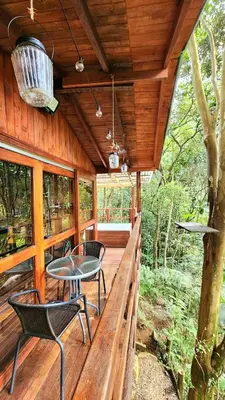 a porch of a cabin with chairs and a table at Cabaña en Medio del Bosque con Jacuzzi - Santa Elena in Santa Elena