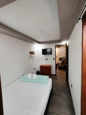 a bedroom with a white bed and a television at Apartamento turístico jardín Antioquia in Jardin
