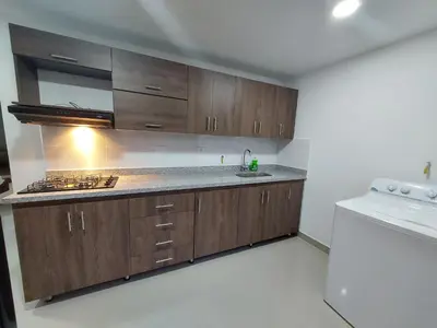 a kitchen with wooden cabinets and a white refrigerator at P.H Downtown - Tranvía in Medellín