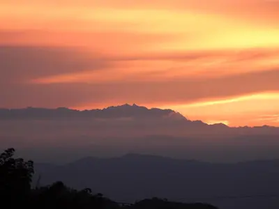 a sunset with clouds and mountains in the background at Bosques de la Pradera in Manizales