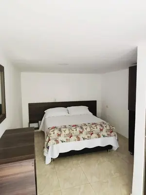 a bedroom with a large bed with white walls at Bosques de la Pradera in Manizales
