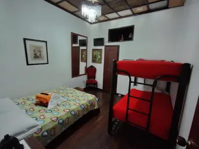 a bedroom with two bunk beds and a red chair at Hostal Mirador Andino in Manizales