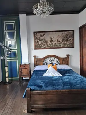 a bedroom with a bed with a blue comforter at Hostal Mirador Andino in Manizales