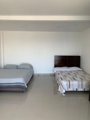 two beds in a room with white walls at Villa NiNa in Manizales