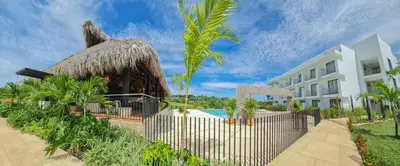 a resort with a thatched building and a swimming pool at Hotel Arbóreo Doradal in Doradal