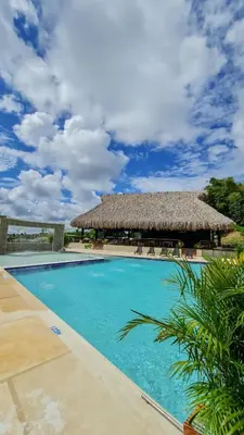 a resort swimming pool with a thatch roof at Hotel Arbóreo Doradal in Doradal