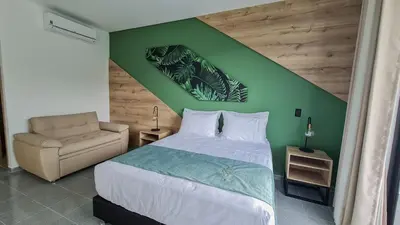 a bedroom with a green wall with a bed and a chair at Hotel Arbóreo Doradal in Doradal