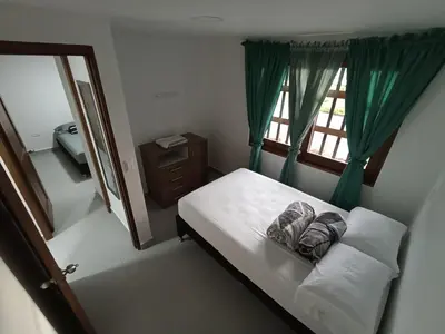 a bedroom with a bed with green curtains and a window at Apartamento El Trébol 101 in Jardin