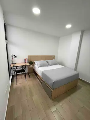 a bedroom with a bed and a desk and a table at 80Cooliving Medellín in Medellín