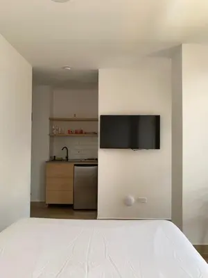 a bedroom with a bed with a television on a wall at 80Cooliving Medellín in Medellín