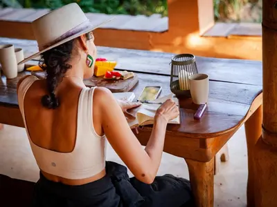 a woman sitting at a table with a cell phone at Ecofinca Fuente Alegre in Cocorná