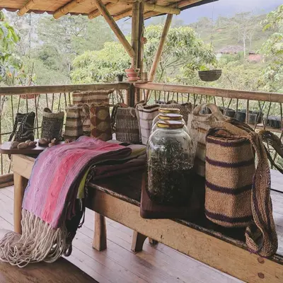 a bench on a porch with a blanket and baskets at Ecofinca Fuente Alegre in Cocorná