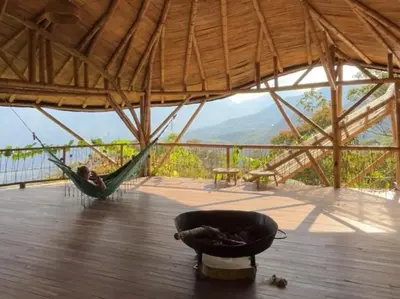 a hammock on a deck with a view of the mountains at Ecofinca Fuente Alegre in Cocorná