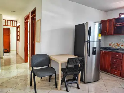a kitchen with a table and a stainless steel refrigerator at Apartamentos con estacionamiento cerca al parque in Támesis